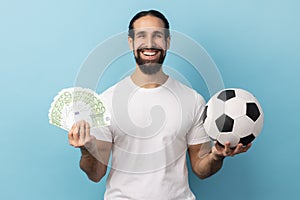 Man showing soccer ball and fun of hundred euro bills, winning lot of money betting for sport.