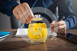 Man showing stethoscope over piggy bank