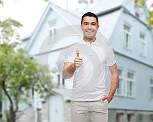 Man showing thumbs up over house background