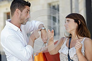 man showing time to girlfriend who wants to continue shopping