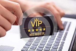 Man Showing VIP Member Card While Using Laptop