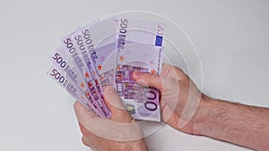 A man shows 3500 euros in 500 euro bills fanned out on white background