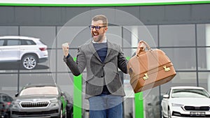 A man shows emotions of happiness after buying a new car near a car dealership