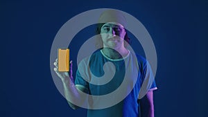 A man shows a green smartphone screen. Portrait of a mustachioed man with a smartphone with a green screen in a studio