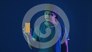 A man shows a green smartphone screen. Portrait of a mustachioed man with a smartphone with a green screen in a studio