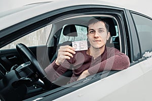 Man shows his driver`s license in the car window immediately after passing the exam or at the request of the traffic