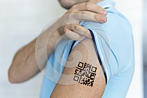 man shows his shoulder with a qr code, a confirmation of the vaccination against the covid 19 coronavirus. Temporary