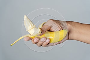 A man shows how to put a condom on his penis using a banana demonstration. Studio shot on a gray background. Empty space