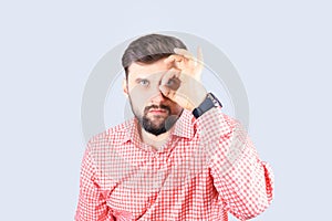 Man shows the ok gesture. A bearded man in a plaid shirt looks through his fingers