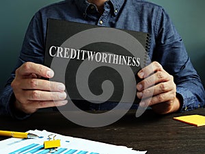 The man shows an sign Creditworthiness on a black page. photo