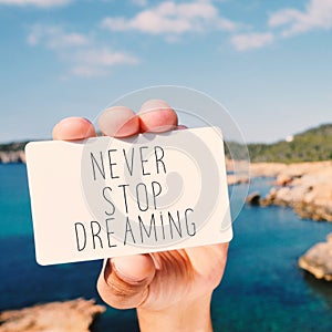 Man shows a signboard with the text never stop dreaming