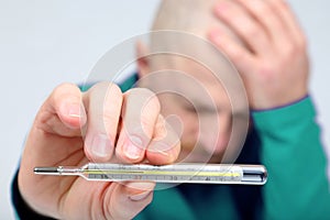 Man shows a thermometer with a high temperature