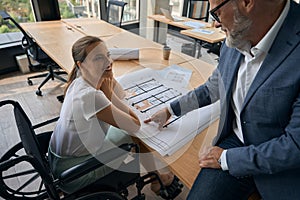 Man shows a woman on a wheelchair a construction plan