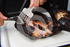 Man shredding pork meat with special claws