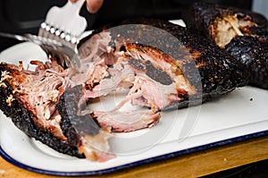 Man shredding pork meat with special claws