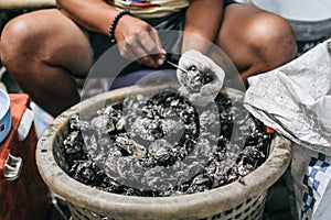 A man shucking a fresh oyster with knife and stainless steel mesh oyster glove for sale at the seafood market.Ready for eat or ser