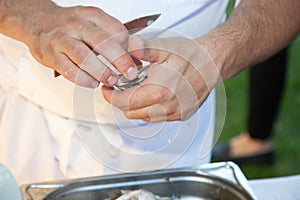 Man shucking fresh oysters with a knife