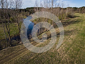 A man with a Siberian husky dog walks in nature near a river in the spring day. Drone view