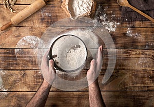 Man sifted flour on the wooden table