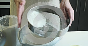 Man Sifting Flour through a Sieve in the Kitchen