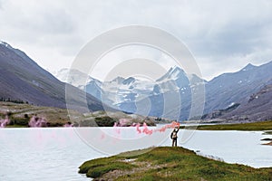 Man with signal fire on background of mountain lake