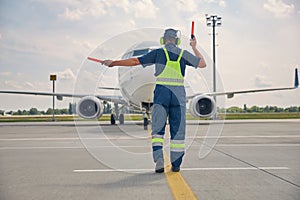 Man signaling the pilot with marshalling wands