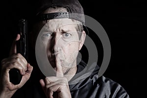 Man signaling to be quite while holding weapon photo