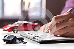 Man signing car insurance document or lease paper. Writing signature on contract or agreement