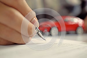 Man signing car insurance document. Writing signature on contract or agreement. Buying or selling new or used vehicle.