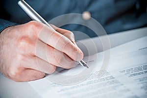 Man signing a document with a fountain pen