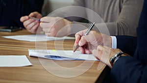 A man signs a document during a business meeting or negotiations. Signing an order, deal, memorandum, agreement or contract. No