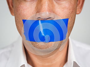 Man is silenced with adhesive red tape across his mouth sealed to prevent him from speaking. Freedom Concept