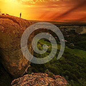 Man silhouette on edge of rock