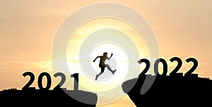 Man silhouette jumping cliff from 2021 to 2022 on cloud sky background. Happy new year 2022. Beginning, challenge, target concept