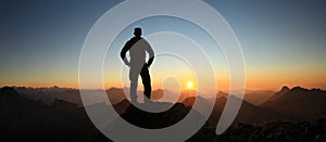 Man Silhouette reaching summit enjoying freedom and looking towards mountains sunset. Allgau Alps, Bavaria, Germany and