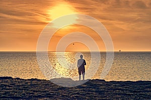 Man silhouette standing on a beach and watching a sunrise