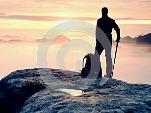 Man silhouette stay on sharp rock peak. Satisfy hiker enjoy view. Tall man on rocky cliff