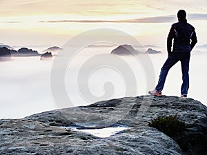 Man silhouette stay on sharp rock peak. Satisfy hiker enjoy view. Tall man on rocky cliff