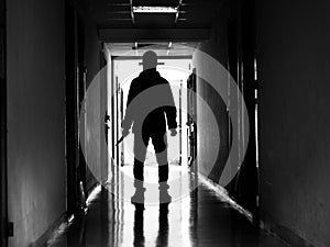 Man silhouette walking away with knife in the light of opening door in dark room, Threat Concept