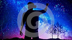 Man silhouette wearing virtual reality glasses in front of digital screen playing with cyber graphic space background