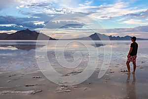 Man sillhoutte walking into sunset of lake Bonneville Salt Flats, Wendover, Western Utah, USA, America. Beautiful summits of