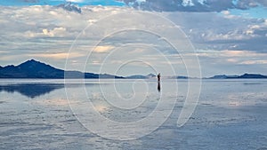 Man sillhoutte walking into sunset of lake Bonneville Salt Flats, Wendover, Western Utah, USA, America. Beautiful summits of