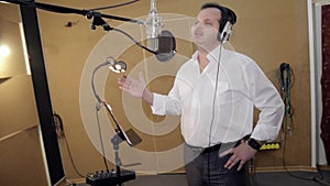 Man sing in headphones in front of microphone. Hand gesticulation. Studio