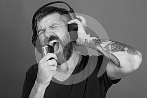 Man sings on green background. Singer with beard and excited face listens to music.