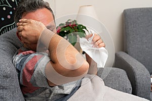 Man with sinusitis headache holding napkin at home feeling unwell