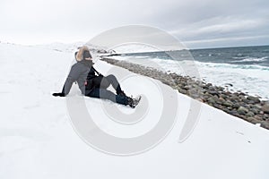 man sit down in a white snow coat travel winter mountains ocean sea.