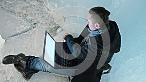 Man is sit on the internet in laptop in an ice cave. Around the mysterious beautiful ice grotto. User communicates in