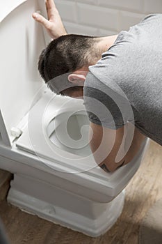 Man sit near the toilet and vomits