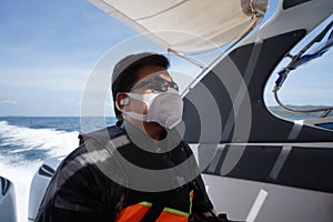 Man sit social distancing on speed boat wear life-saving jacket and protective face mask