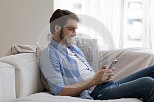 Man sit on sofa holding smartphone share messages through messenger